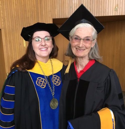 two women in standing in graduation cap and gowns
