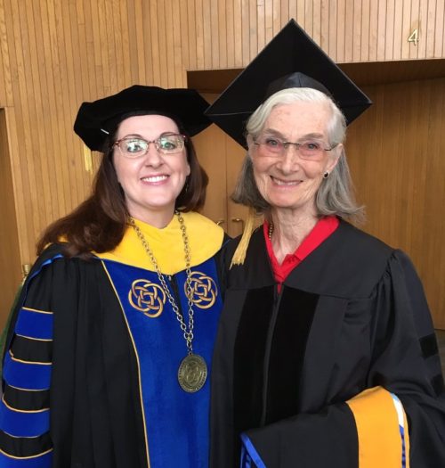 two women in standing in graduation cap and gowns