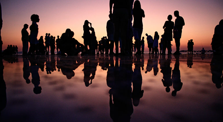 people at the beach during pink sunset