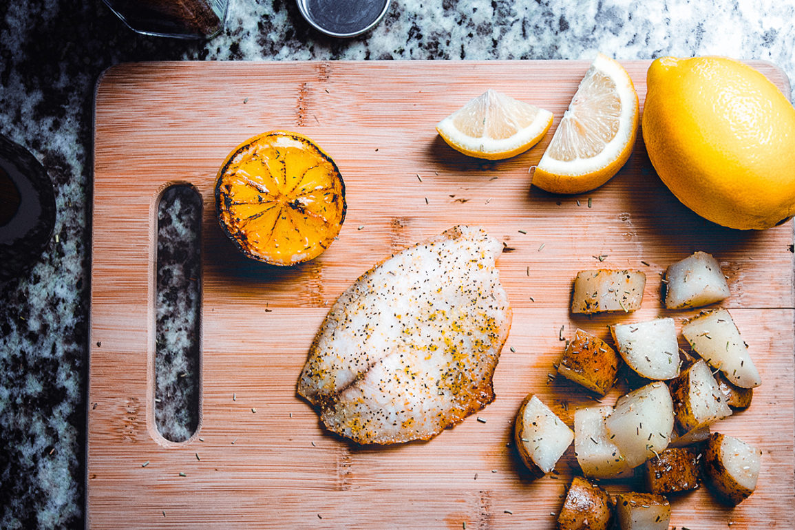 fish, potatoes, and lemon on a cutting board to demonstrate culinary psychology
