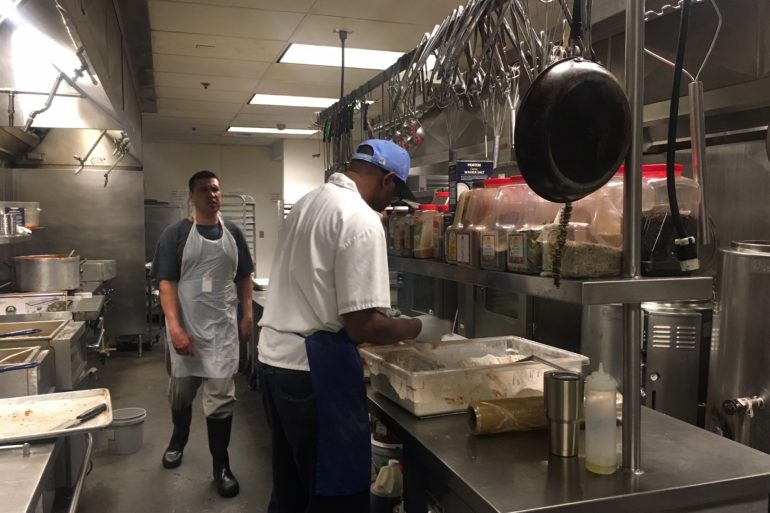 man in blue hat cooking in commercial kitchen