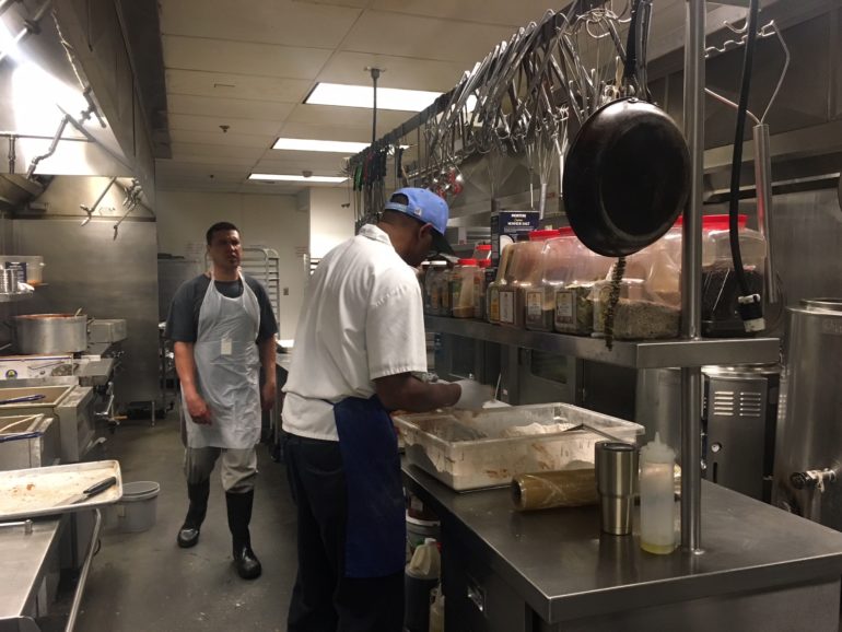 man in blue hat cooking in commercial kitchen