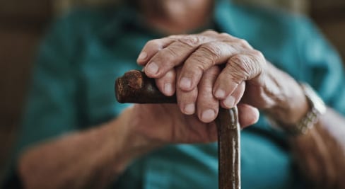 old hands on top of a cane