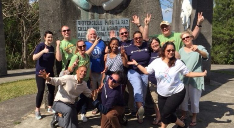 large group of people posing by stone monument