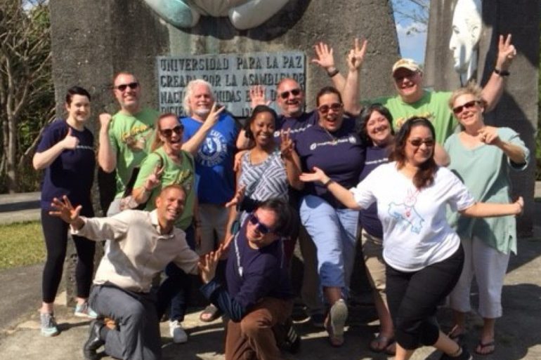 large group of people posing by stone monument