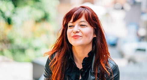 woman with red hair and black jacket smiling