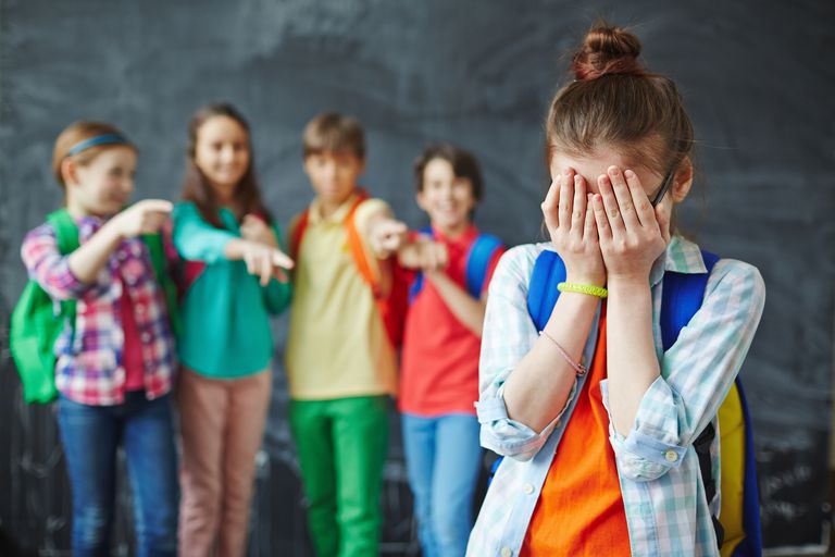 four kids point at lonely student covering her face