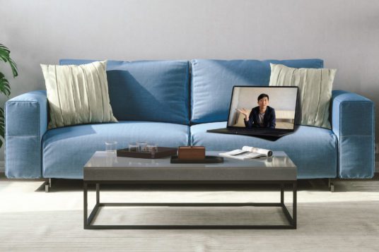 Couch and coffee table with laptop on couch displaying image of a person