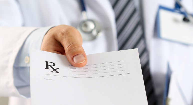 Close-up of doctor's hand holing a prescription