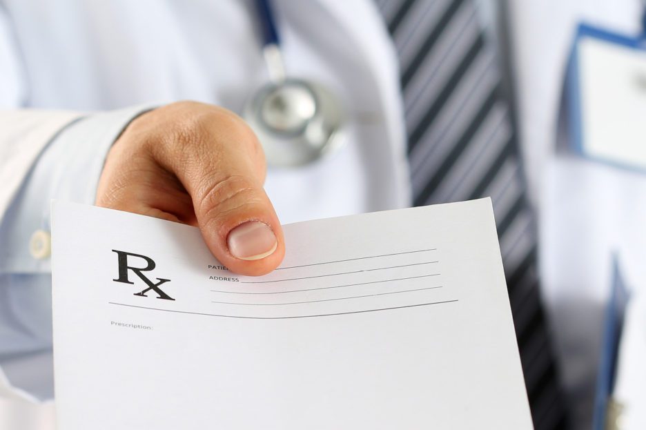 Close-up of doctor's hand holing a prescription