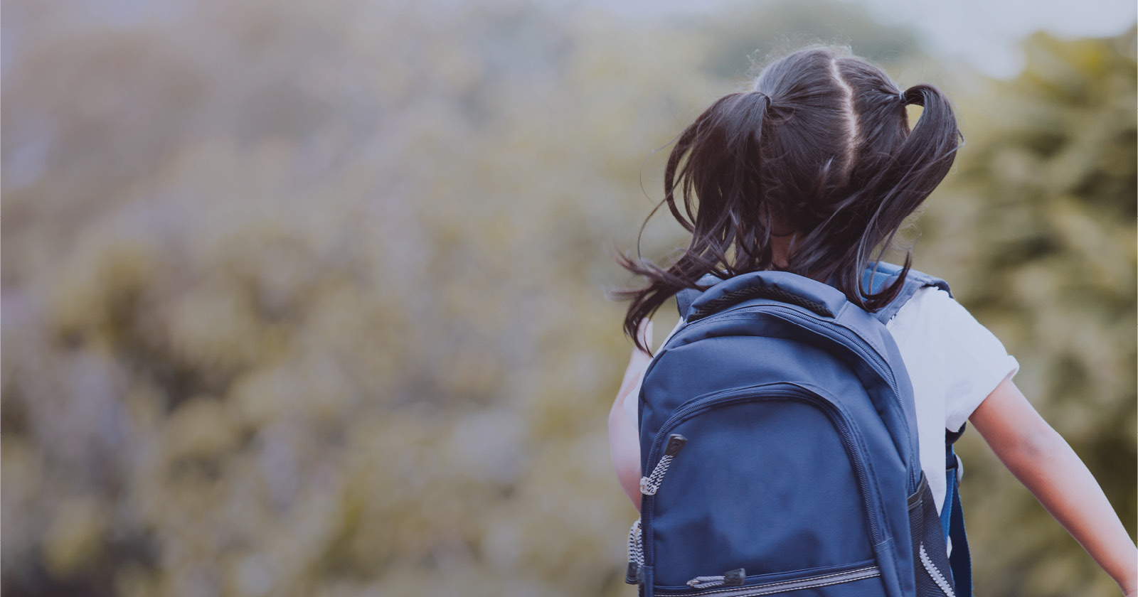 Image of a child running from behind while wearing a backpack.