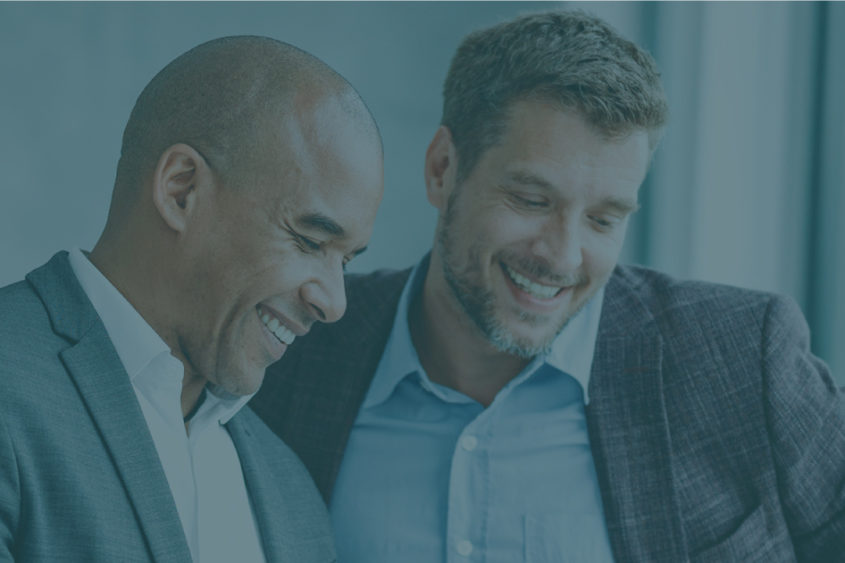 Photo of two business men talking and smiling.
