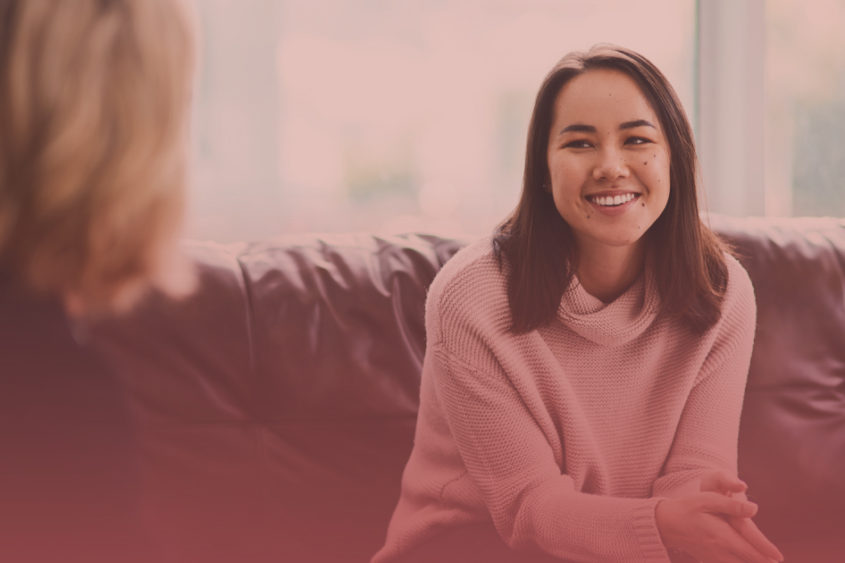 Photo of a young woman talking to a therapist and smiling.
