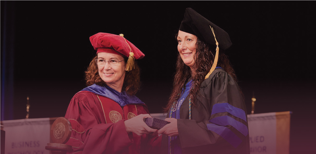 Photo of The Chicago School graduate Natalie Paquet Croteau receiving her diploma at commencement.