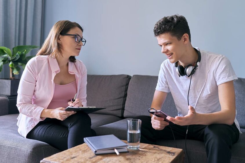 teenage male talking with woman holding clipboard