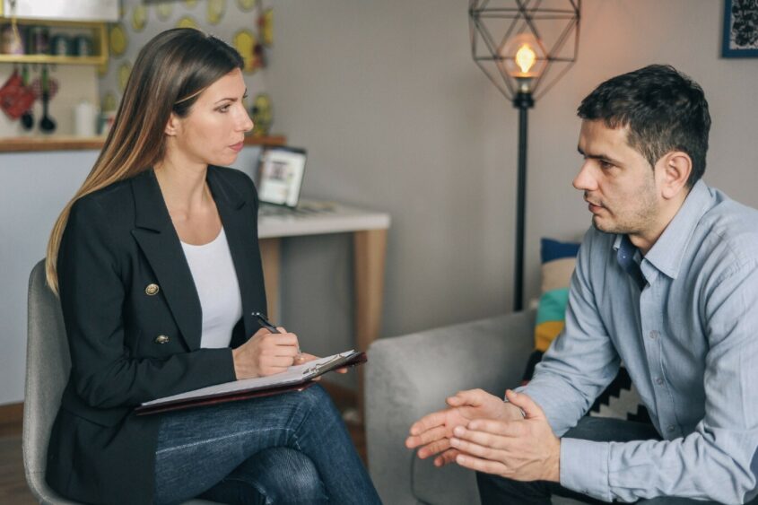 man talking to woman holding a clipboard