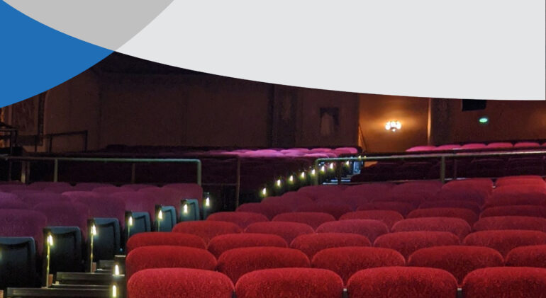 A movie theater with rows of red seats sits empty.