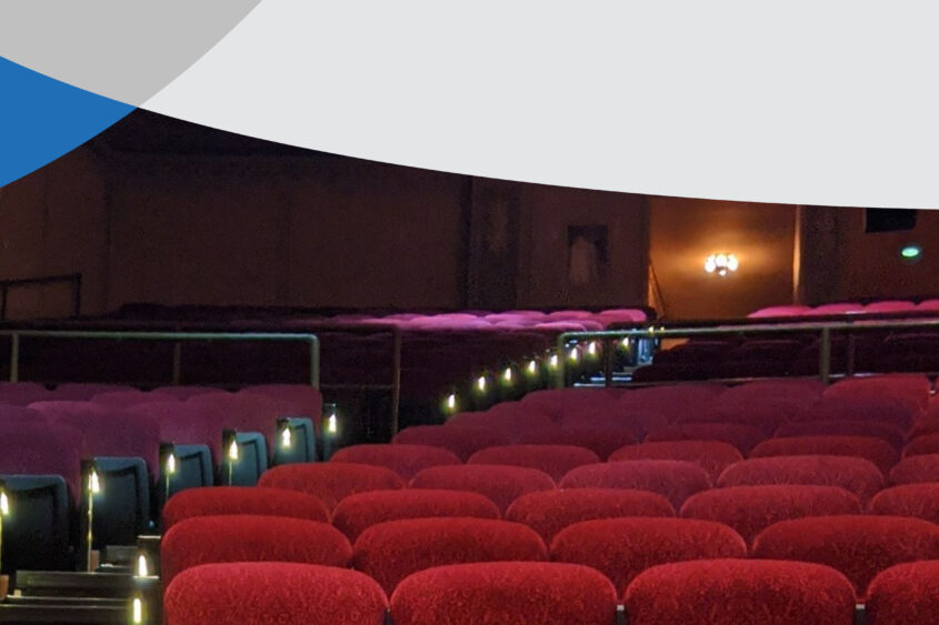 A movie theater with rows of red seats sits empty.