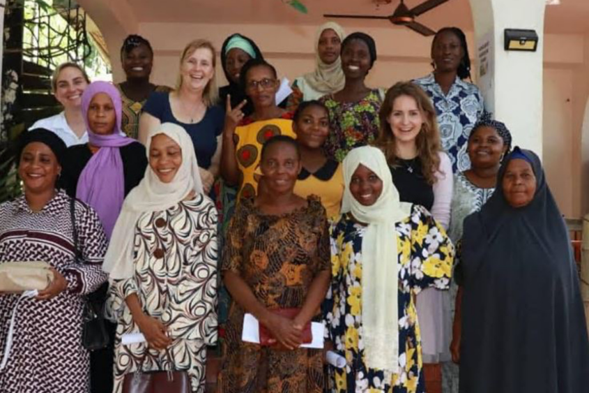 The Chicago School's Drs. Kate Green and Kelly Torres pose and smile in a group photo with staff at an early learning center in Tanzania.