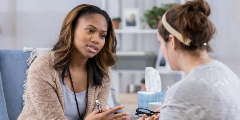 A therapist talks with a client and gestures with her hands.