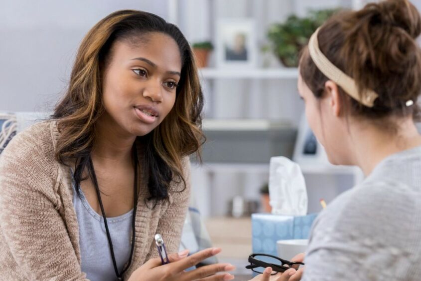 A therapist talks with a client and gestures with her hands.