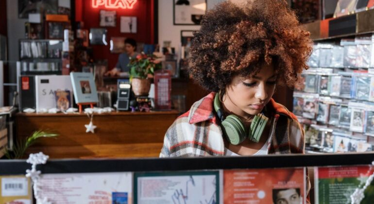 A young woman with headphones around her neck shops at a record store.