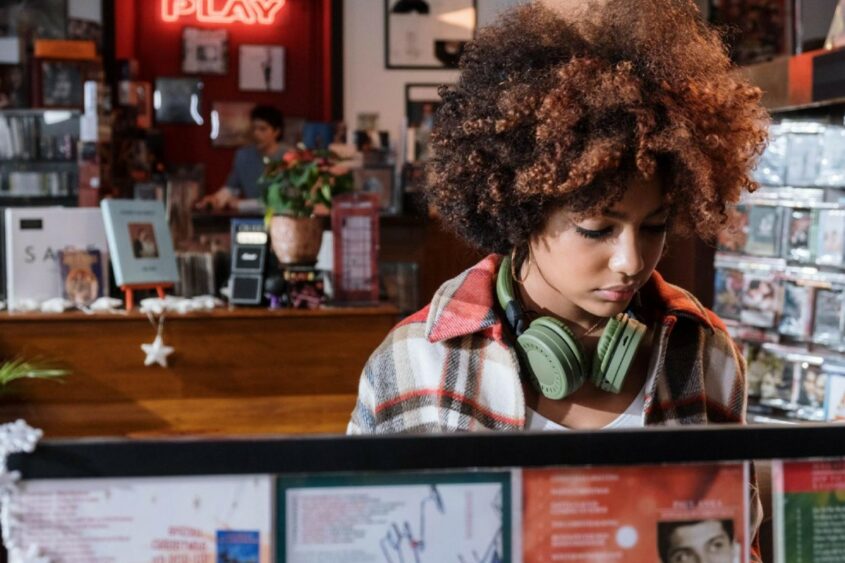 A young woman with headphones around her neck shops at a record store.