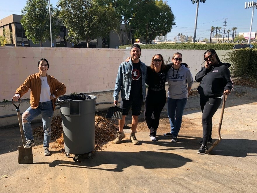 Members of The Chicago School's Community Partnerships community pose outside with shovels and a trash can.