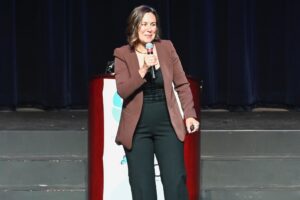 Heather Bodie speaks on stage with microphone.