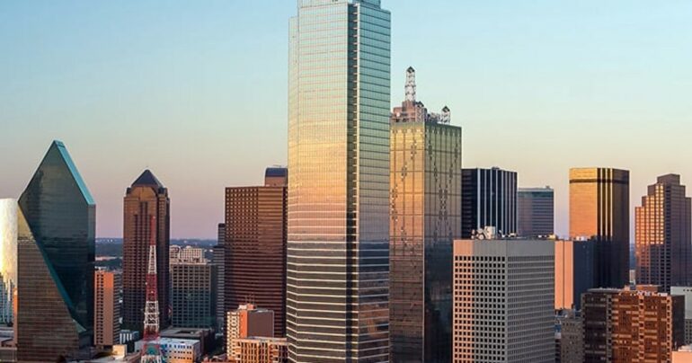 The skyline of Dallas, Texas appears against a bright blue sky.