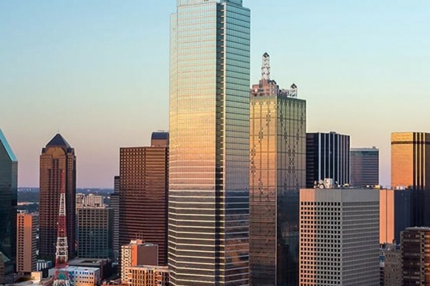 The skyline of Dallas, Texas appears against a bright blue sky.
