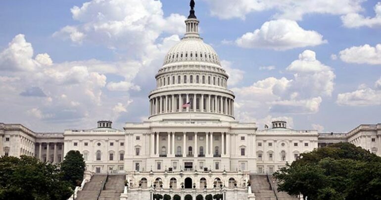The United States Capitol appears against a bright blue sky.