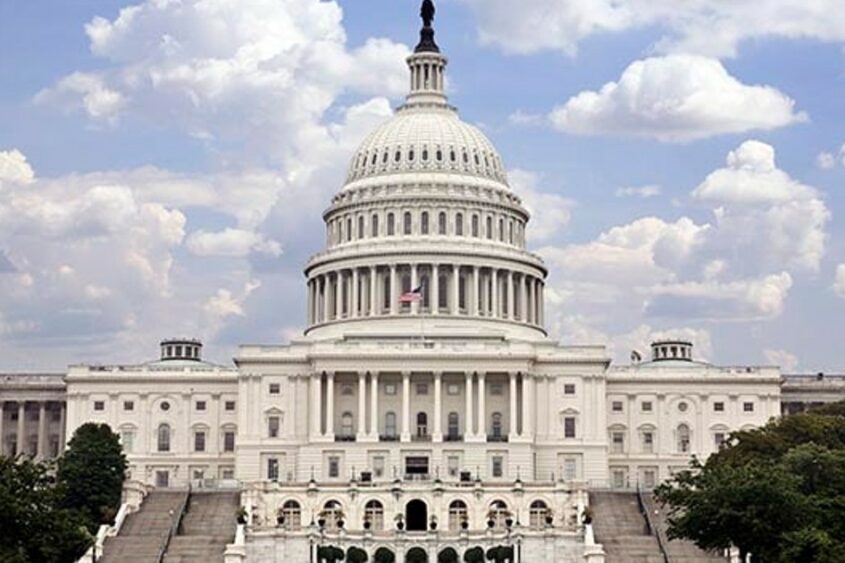 The United States Capitol appears against a bright blue sky.