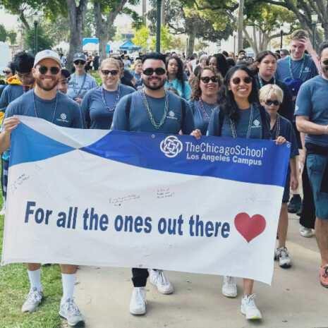 The Chicago School students walk in tandem while holding a sign that reads "For All the Ones Out There" followed by a heart symbol.