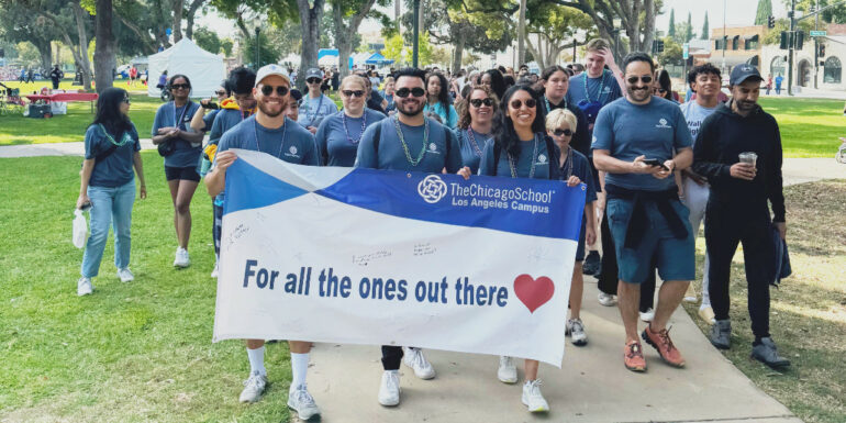 The Chicago School students walk in tandem while holding a sign that reads "For All the Ones Out There" followed by a heart symbol.
