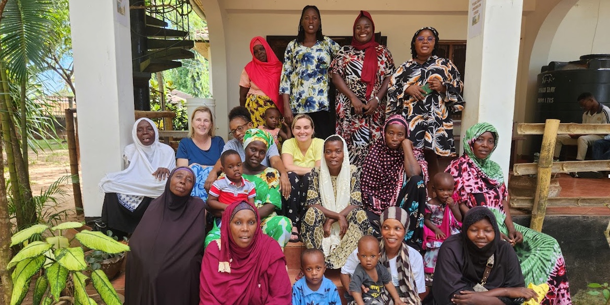 The Chicago School's Drs. Kate Green and Kelly Torres pose and smile in a group photo with staff at an early learning center in Tanzania.
