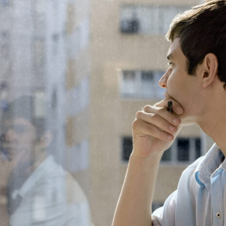 student with laptop looking out a window.
