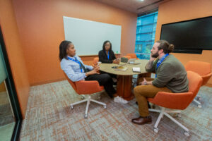 Two women and a man sitting at a conference table.