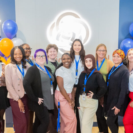 A group of adult students posing in front of the logo of The Chicago School.