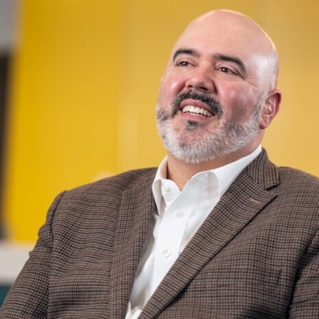 IllinoisCOM Founding Dean and Chief Academic Officer John Lucas, DO, smiles and looks off-camera into the middle distance.