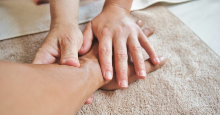 Occupational therapist using hands-on therapy techniques on a patient's wrist and hand.