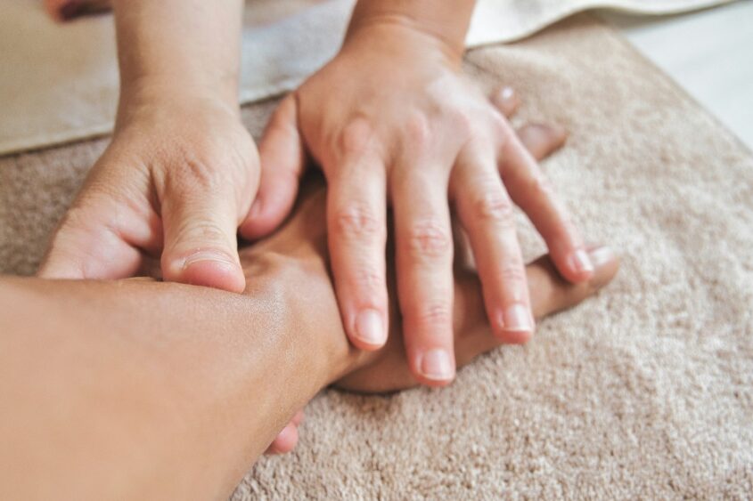 Occupational therapist using hands-on therapy techniques on a patient's wrist and hand.