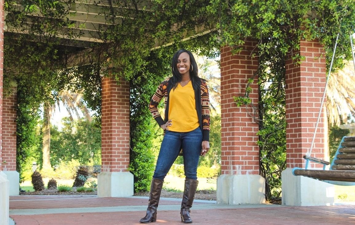 woman in yellow posing near brick columns