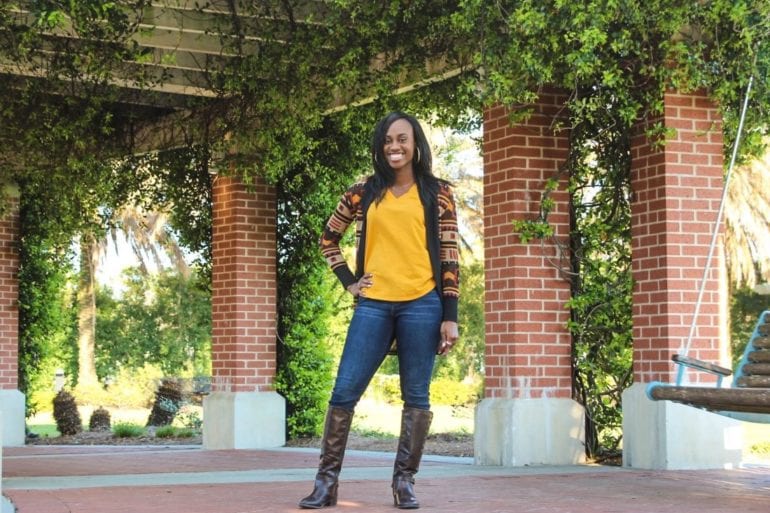 woman in yellow posing near brick columns