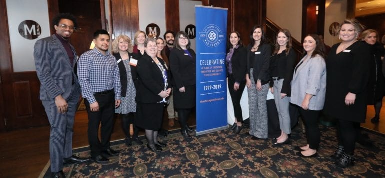 group of people standing near 40 year celebration banner