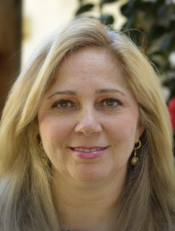 woman with blonde hair and gold earrings looking at the camera