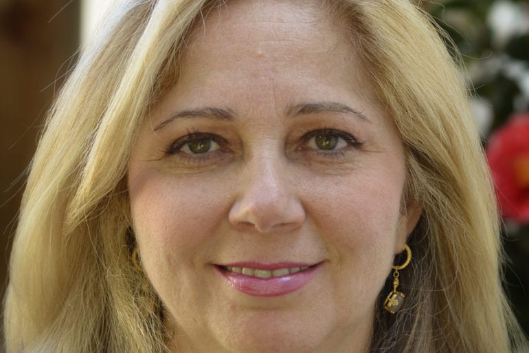 woman with blonde hair and gold earrings looking at the camera