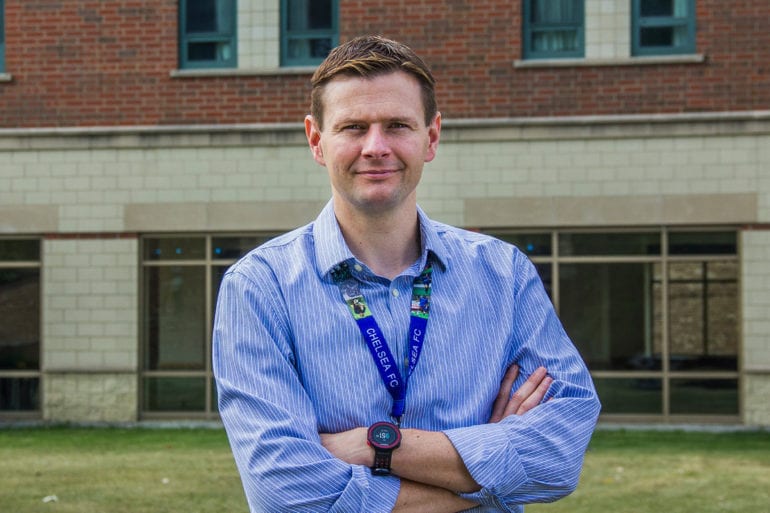 man in blue striped shirt with arms crossed