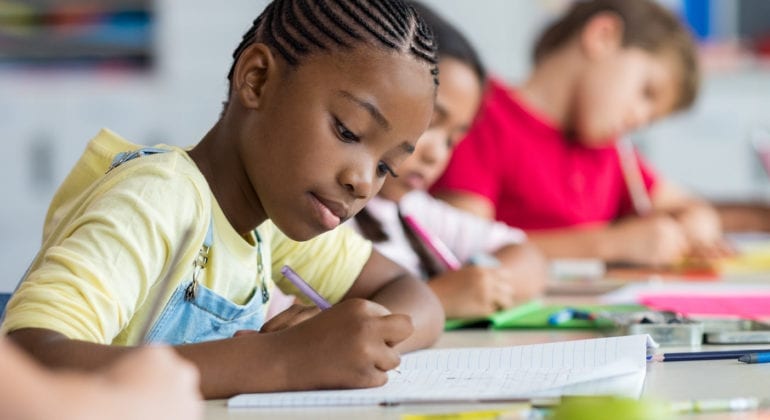 young girl in yellow shirt writing