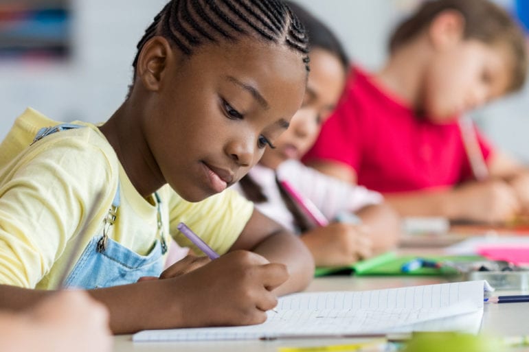 young girl in yellow shirt writing